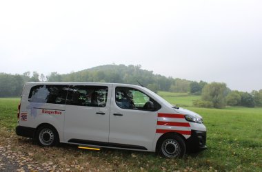 Der Bürgerbus der auf einer Wiese vor dem Wald steht