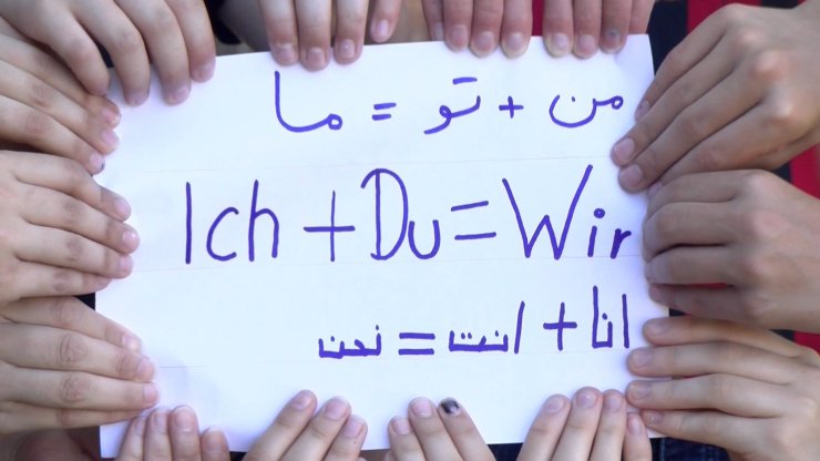 Kinder Hände halten ein Bild Mehrere Kinderhände halten ein Blatt in der hand wo Ich+Du=Wir drauf steht in verschiedenen sprachen