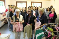 Kleidertüte In der Kleidertüte sind mehrere Menschen aus verschiedener herkunft stehen dort drinnen mit Kinder Kleidung in der Hand.