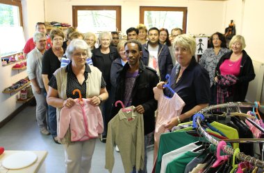 Kleidertüte In der Kleidertüte sind mehrere Menschen aus verschiedener herkunft stehen dort drinnen mit Kinder Kleidung in der Hand.