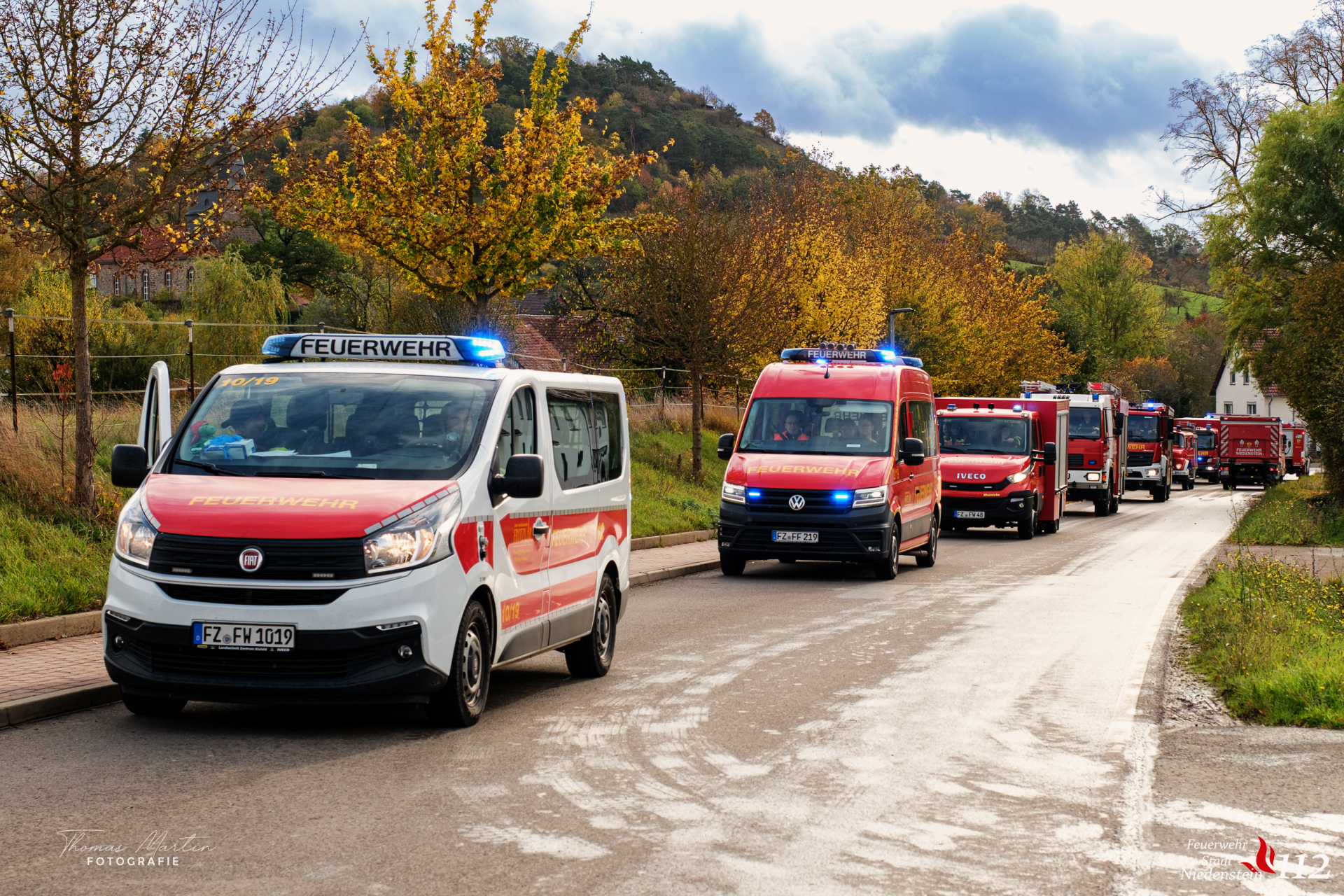 Feuerwehrmänner holen hier stehen am und laufen um ein Einsatzfahrzeug mit geöffneten Rolläden