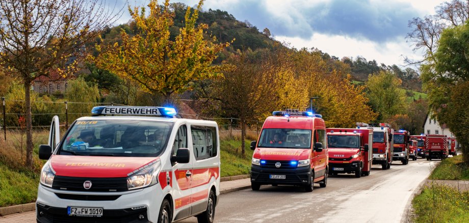 Feuerwehrmänner holen hier stehen am und laufen um ein Einsatzfahrzeug mit geöffneten Rolläden